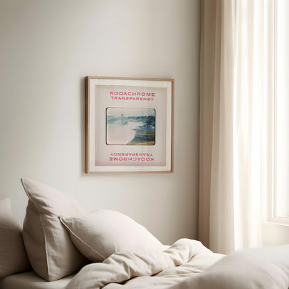a framed poster of a scenic landscape hanging on a wall in a bedroom.