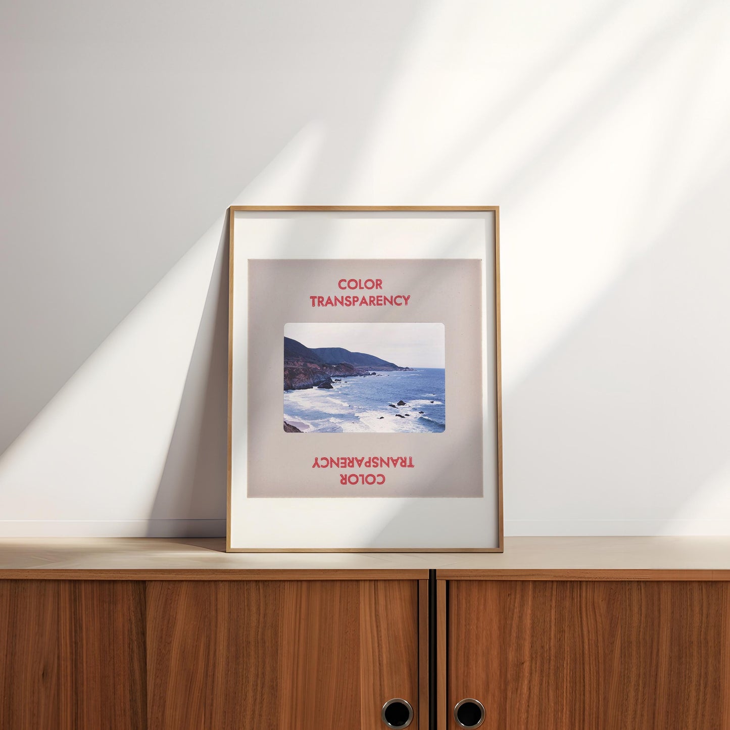 a framed photograph of a coastal landscape, with the text "COLOR TRANSPARENCY" and "COOL COLOR" visible on the frame.