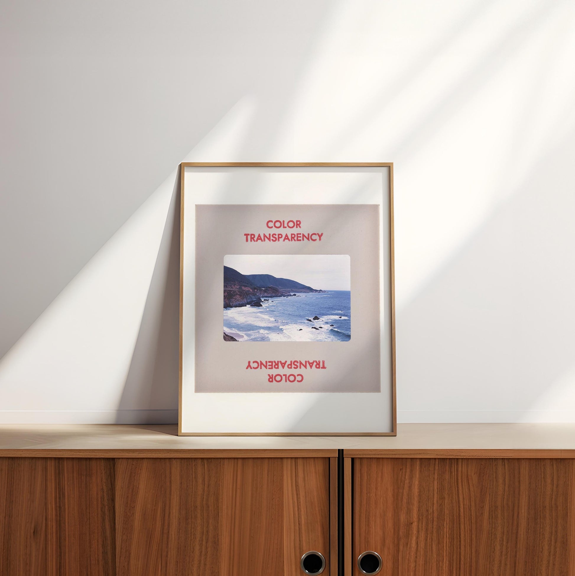 a framed photograph of a coastal landscape, with the text "COLOR TRANSPARENCY" and "COOL COLOR" visible on the frame.
