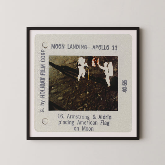 The image is a framed slide from a movie depicting the Apollo 11 moon landing, showing two astronauts walking on the surface of the moon.