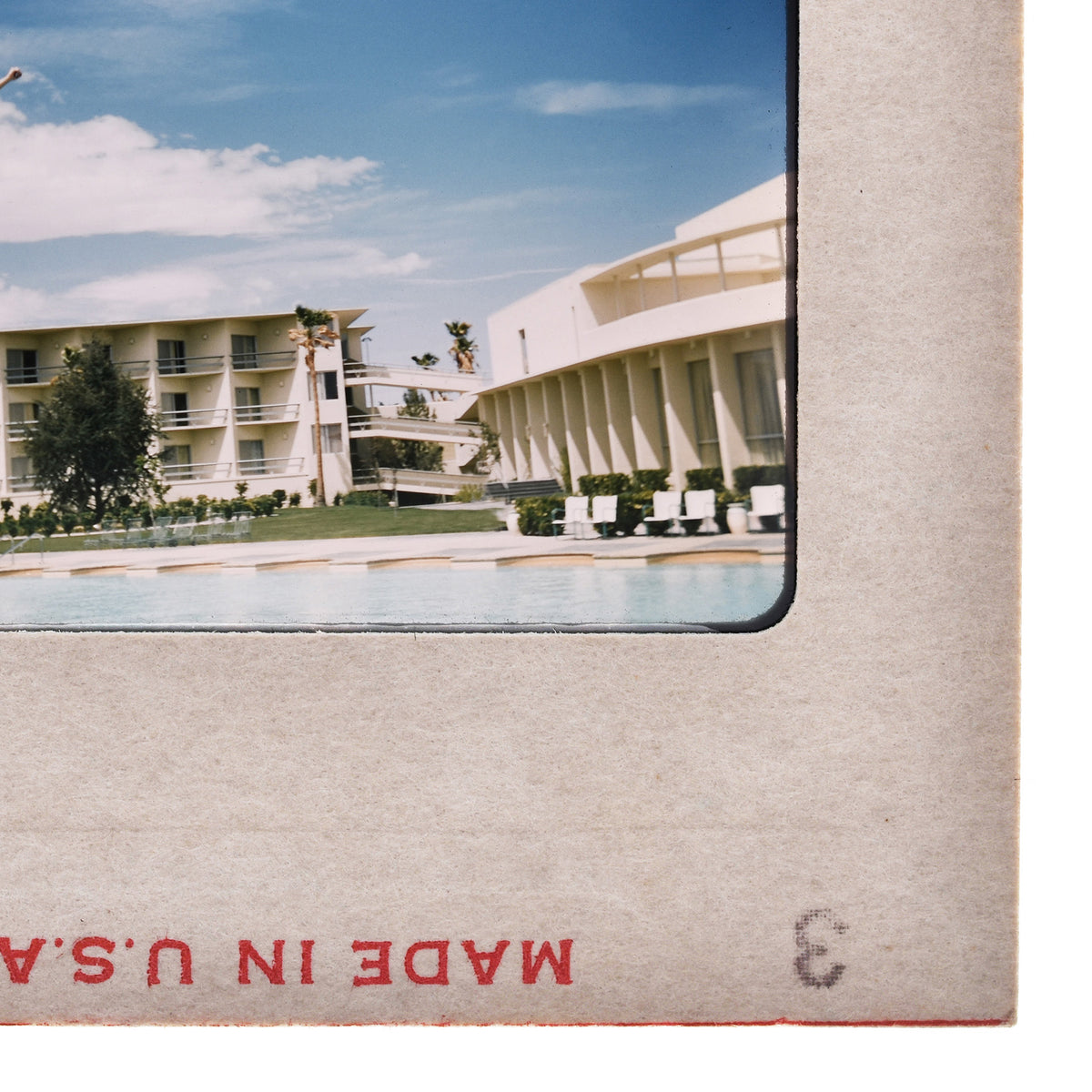 a hotel with a swimming pool in the foreground, and a large white building with a curved roof in the background.
