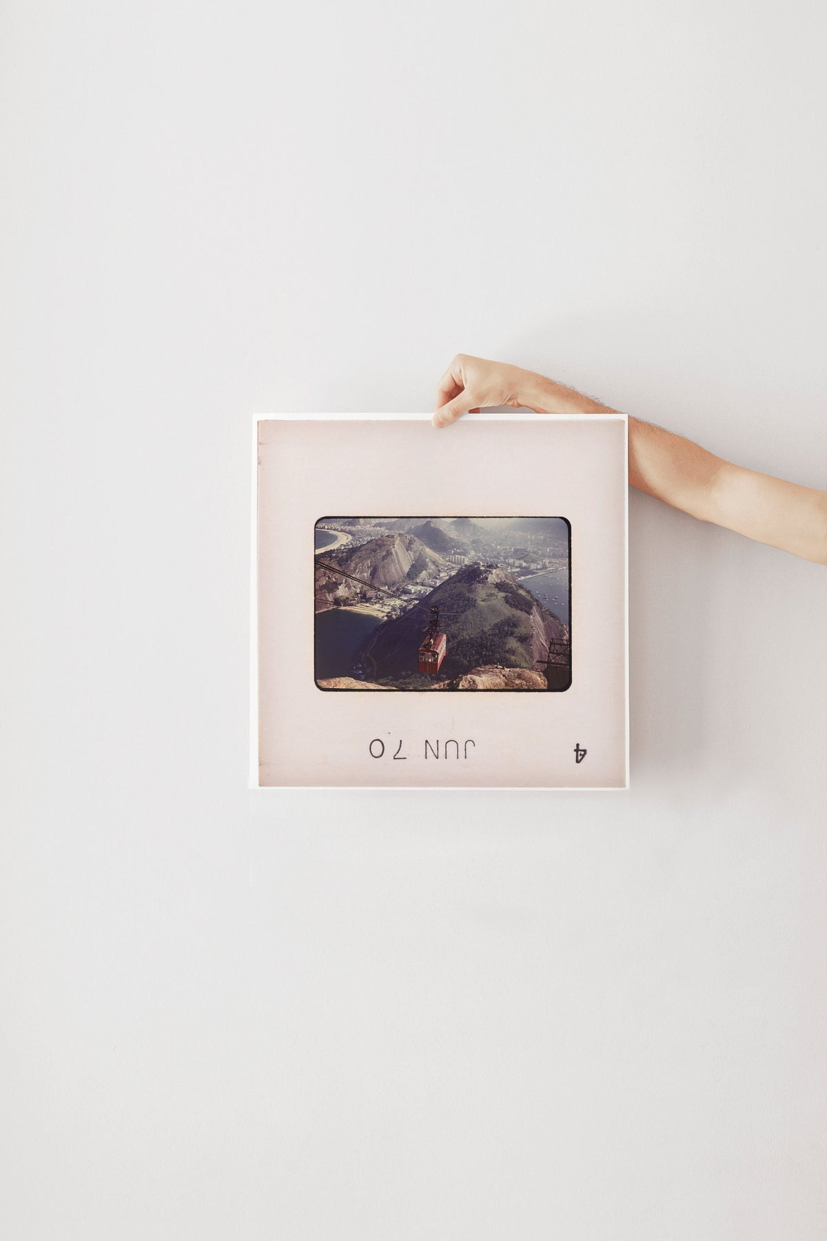 A person's hand is holding a framed photograph of a mountainous landscape.
