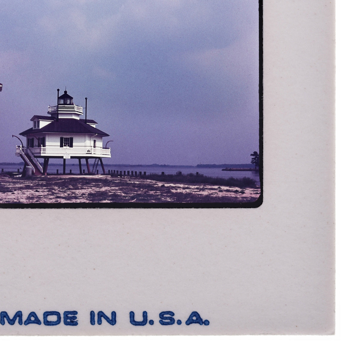 A lighthouse on a beach with a body of water in the background.