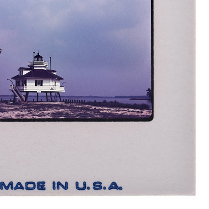 A lighthouse on a beach with a body of water in the background.