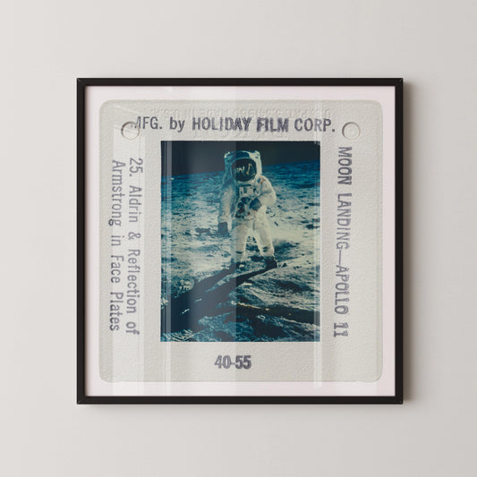 The image is a framed photograph of an astronaut in a spacesuit on the moon's surface, with the text "Moon Landing - Apollo 11" and "40-55" visible.