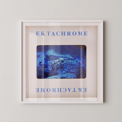 The image is a framed artwork depicting a person in a white suit standing in a blue underwater scene.