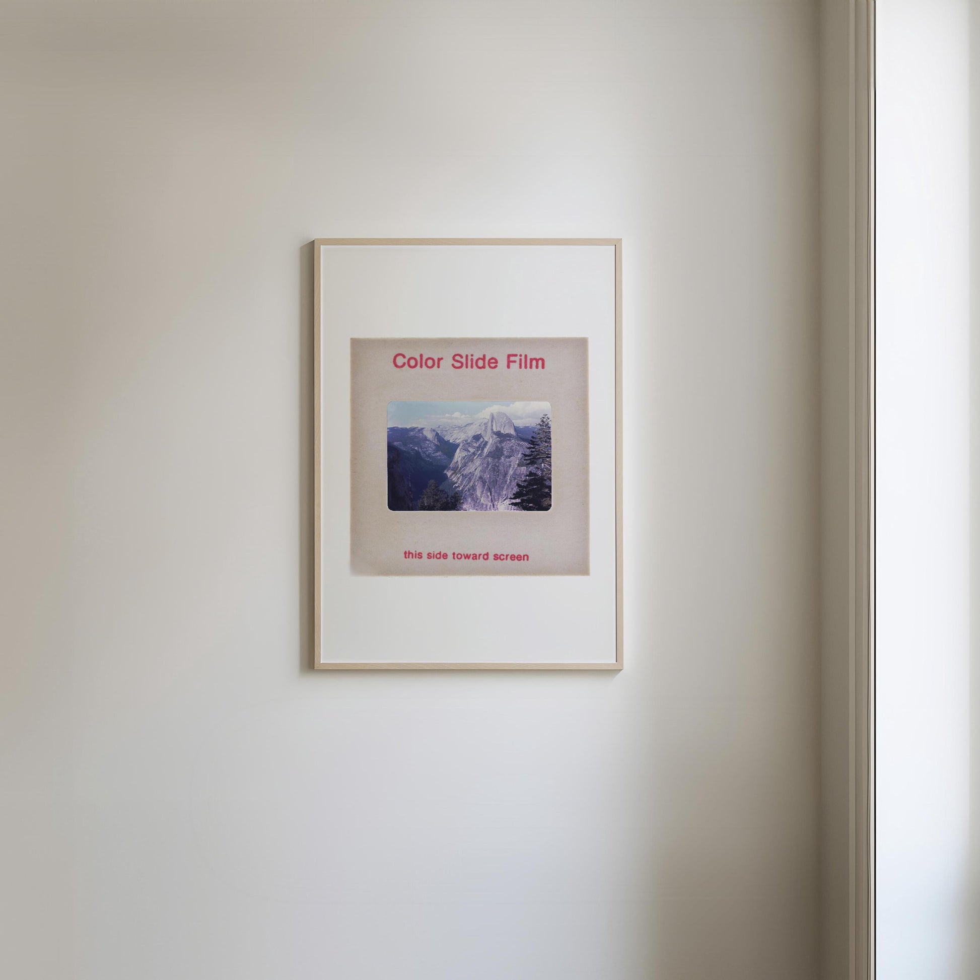 The image is a framed photograph of a mountain landscape, hanging on a wall.