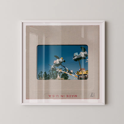 The image is a framed photograph of a carnival ride, featuring a large, colorful structure with various rides and attractions.