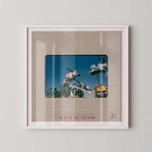 The image is a framed photograph of a carnival ride, featuring a large, colorful structure with various rides and attractions.