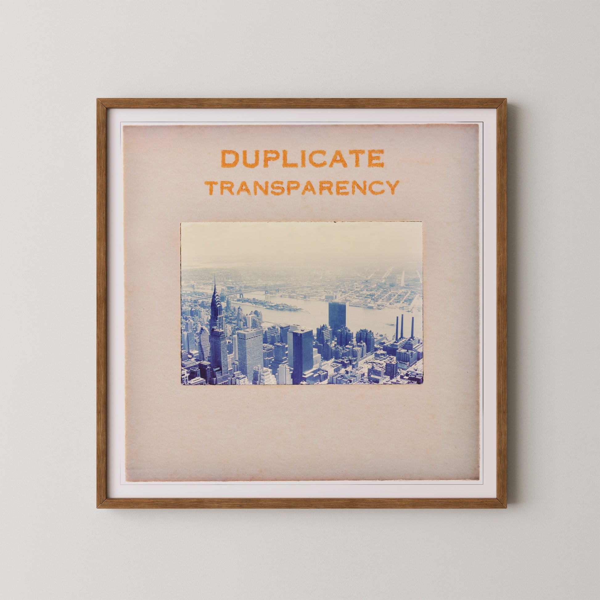 The image is a framed print of a cityscape, with the text "DUPLICATE TRANSPARENCY" prominently displayed above the photograph.