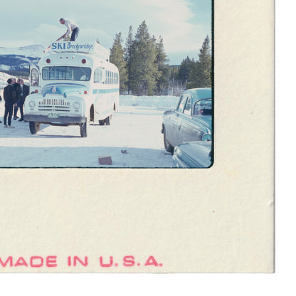 A vintage ski bus parked in a snowy landscape, with people standing nearby.