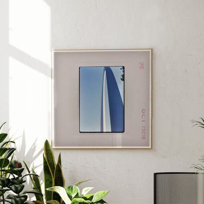 a framed photograph of a blue and white sailboat on a sunny day, hanging on a white wall.