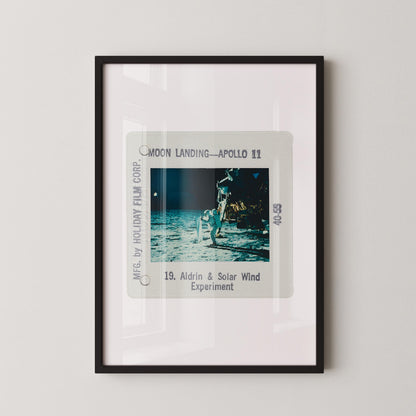 The image is a framed photograph of the Apollo 11 moon landing, depicting the astronaut walking on the surface of the moon.