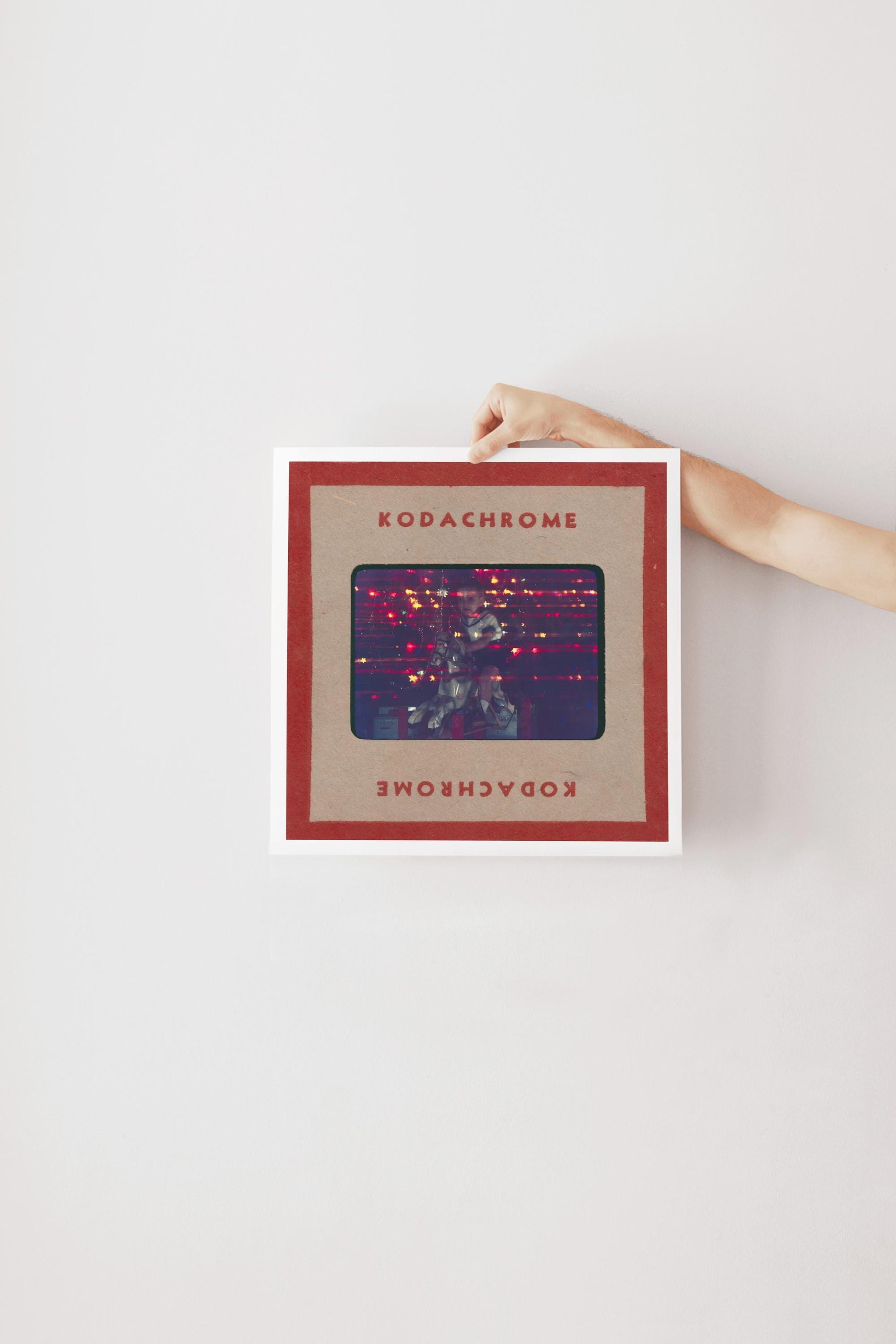 A person's hand is holding a framed image with the text "KODACHrome" on it.