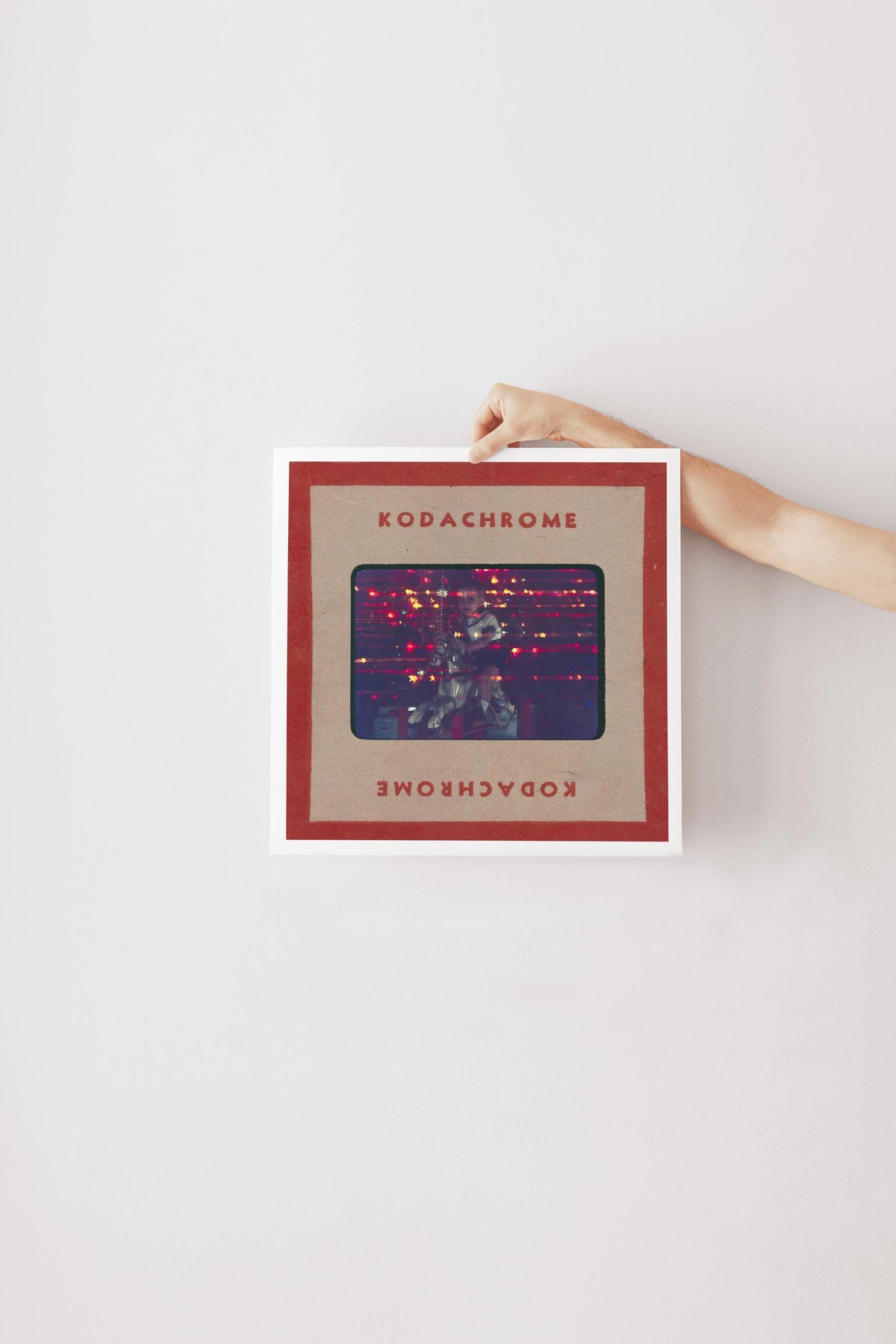 A person's hand is holding a framed image with the text "KODACHrome" on it.