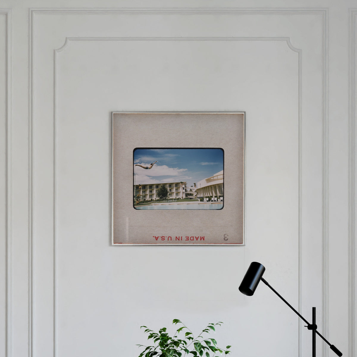 a framed photograph of a building with a plane flying overhead, hanging on a white wall.