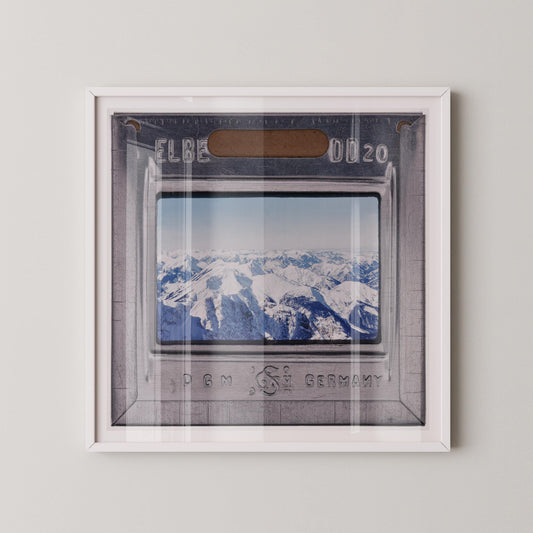 The image is a framed photograph of a snowy mountain landscape, with the text "ELBE 0020" visible on the frame.