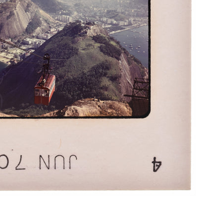 a cable car system suspended above a mountainous landscape, with a city visible in the background.