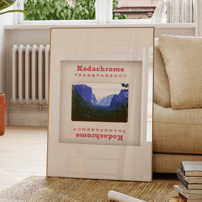 A framed photograph of a mountainous landscape is displayed on a wooden floor in a living room.