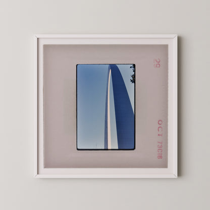 a framed photograph of a tall, blue structure with a white stripe, displayed on a wall.